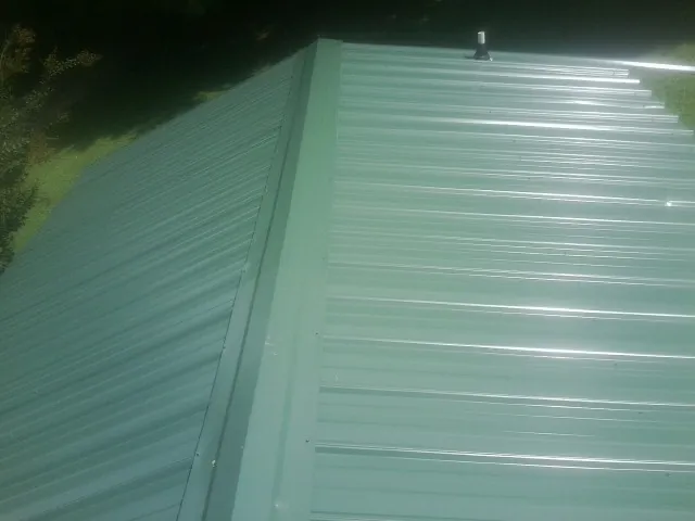 New green metal panels meeting at the ridge of a roof — Flat Roof Repair work by our crew in Brightwood