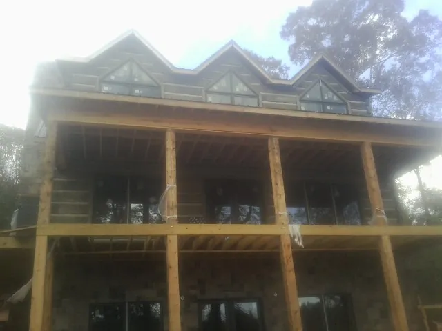 Dormers and porch framing on a large log home under construction — Roof Coating work by our crew in Brightwood