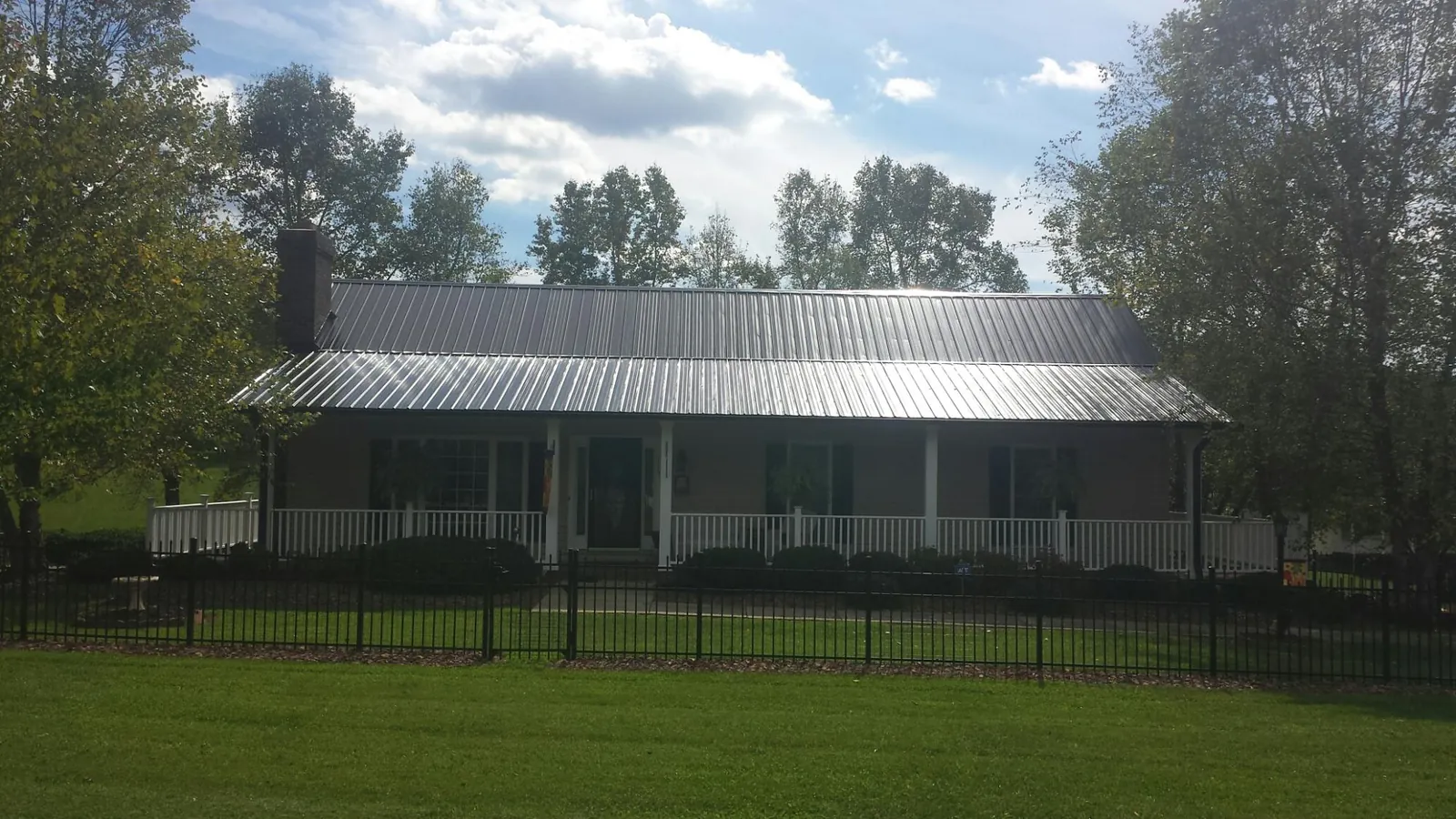 Gray metal roof on a brick ranch with a full width front porch — Gutter Guard Installation work by our crew in Brightwood