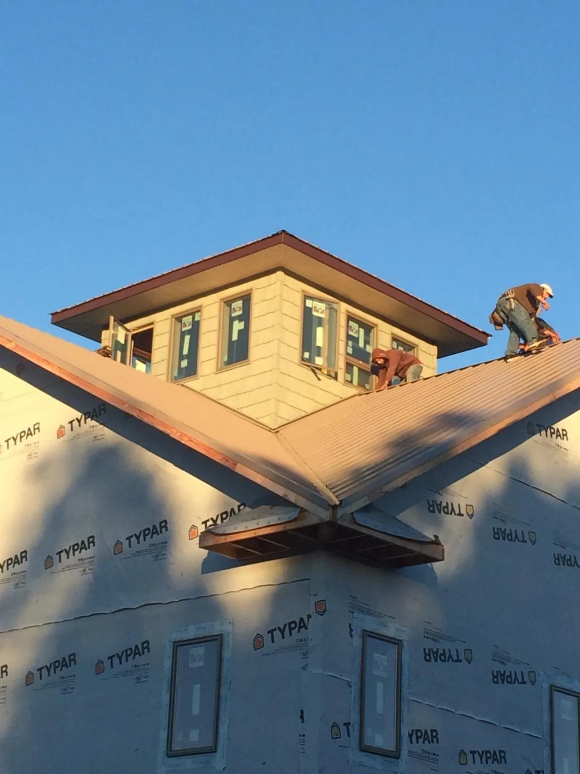 Roofers working around a rooftop cupola on a new metal roof at sunset — Roof Waterproofing in Brightwood by Roofing Brothers